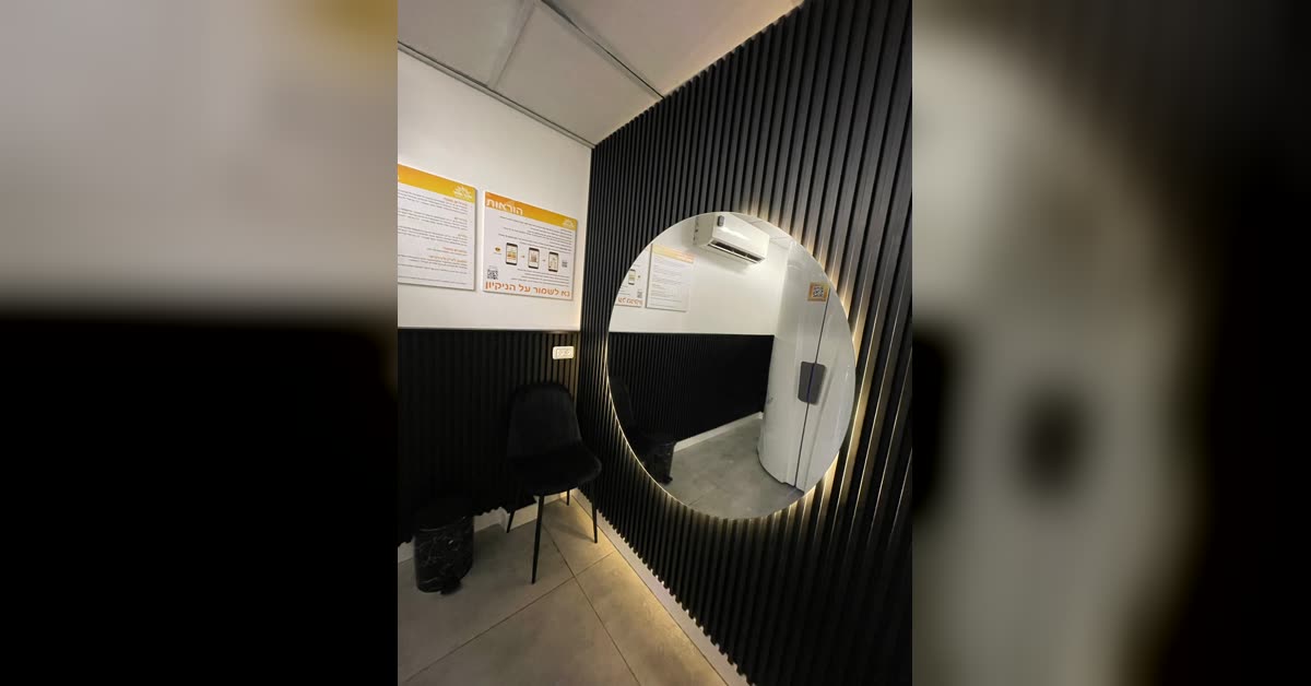 חדר שיזוף עם מראה עגולה מוארת ומכונה — מיני סאן וייב חולון
