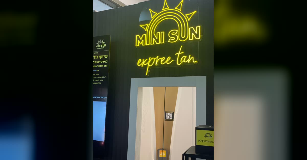 שלט ניאון MINI SUN express tan מעל כניסת החדר — מיני סאן הולמס פלייס ראשון לציון